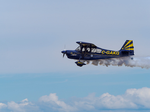 Hillsboro, Oregon, USA - May 22, 2022 :   Anna Serbinenko, PhD in a Super Decathlon aerobatic airplane. Flying with a white trail of smoke. The Air Show in Hillsboro, Oregon is a very popular event each year. The theme for 2022 was “She Flies with her own wings.” All performers, pilots and announcers were women. Hillsboro is a suburb of the city of Portland, Oregon.