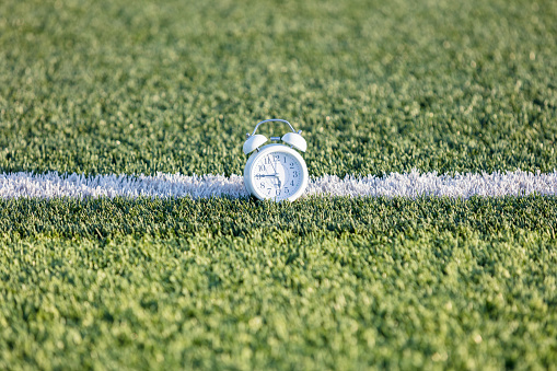 Alarm clock placed on white markings on sports lawn