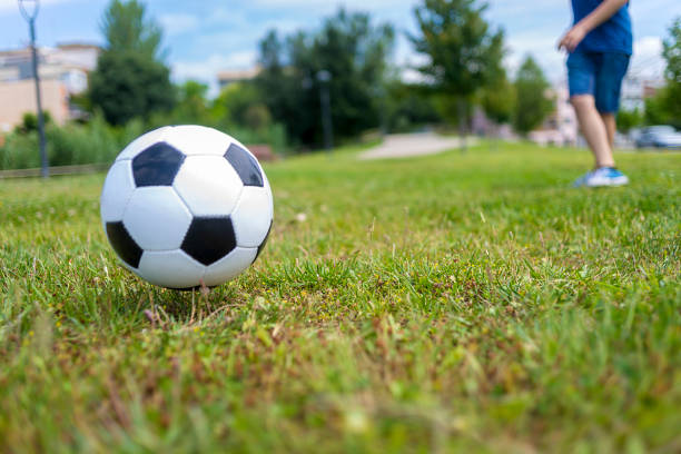 istock Low angle view of a ball on park grass kicked by a child 1402064492