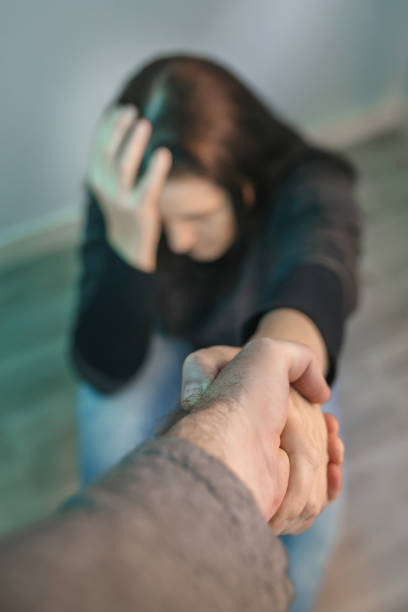 unrecognizable woman with mental disorder receiving help from man holding her hand - mockery imagens e fotografias de stock