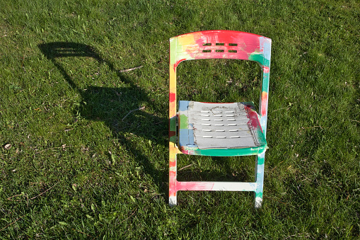 white plastic chair with multicolored paint spots outdoors