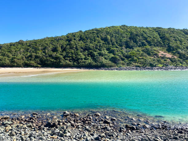 istock Looking out at the beach over some dark bolder rocks into the blue pacific ocean.  Burleigh Headland in the distance.  Blue skies above.  Tallebudgera Creek Gold Coast Queensland Australia. 1402068172