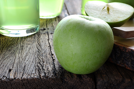 Fresh apple juice and green apple on the wooden table. Healthy drink concept. Selective focus