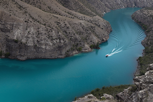 Beautiful turquoise mountain river Sulak with pleasure boat in depth steep canyon. Mountain landscape. Adventure, tourism and travel in wild majestic Caucasus ridges mountains.