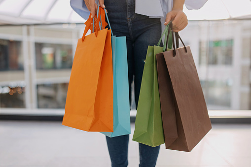 Woman is holding a lot of  paper bags in her hands after shopping. Close up