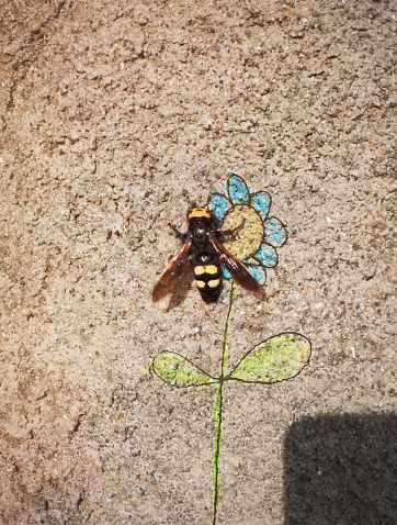 A large bee is on a flower... sketched onto a wall. *** The artwork was digitally superimposed and a release is provided ***