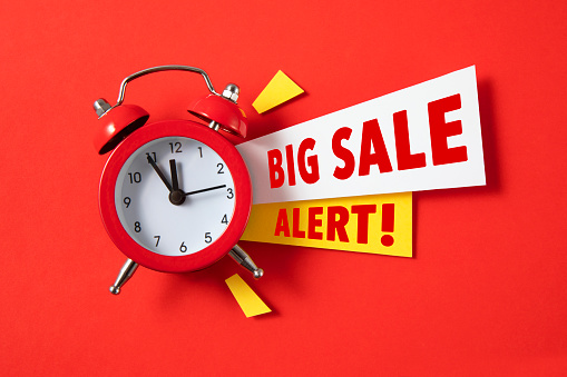 Red alarm clock with colored papers and big sale alert text on red background