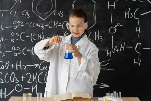 Female high school student performing experiment in chemistry lab, schoolgirl taking care of experiments in chemistry class, use a pipette for liquid in a flask, educational concept