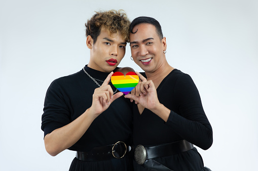 Asian gay man couple in black dress holding rainbow paper cut heart for lgbt lgbtq and lgbtq+ concept posing and looking camera on the white background.
