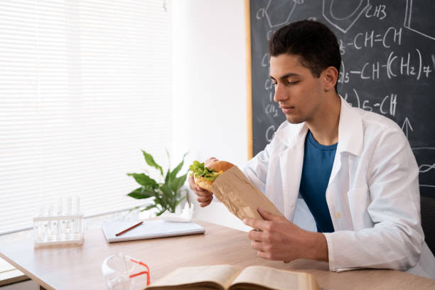istock young male worker of food control eating hamburger by workplace while checking quality and taste of its ingredients in laboratory 1402076609