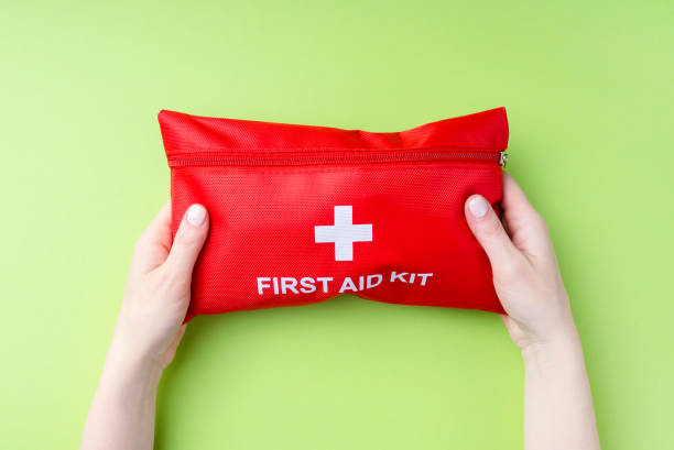 istock Red first aid kit in female hands on a green background. 1402076782