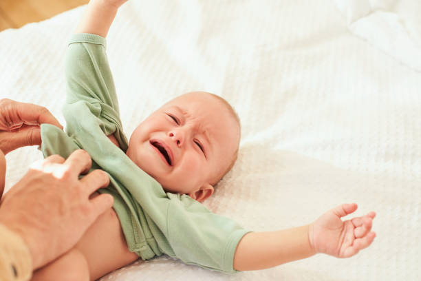 istock A crying newborn baby in a green bodysuit. 1402081674