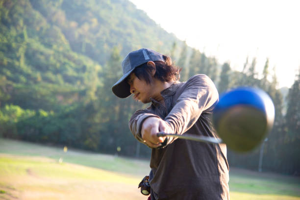 golfista asiático man swing golf ball practice at golf driving range on evening on time for healthy sport. concepto de estilo de vida y deporte - golf expertise professional sport men fotografías e imágenes de stock