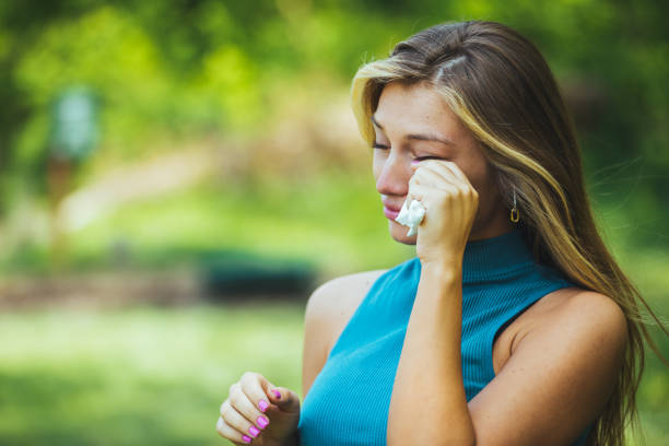 istock Young woman sneezing in park. 1402085820