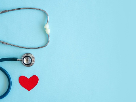 A stethoscope with a red heart on a blue background with a place for text, a Doctor's Day concept, top view.