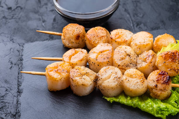 Scallop skewers close-up on dark slate, dark background. Scallop skewers close-up on dark slate, dark background. chicken skewer stock pictures, royalty-free photos & images