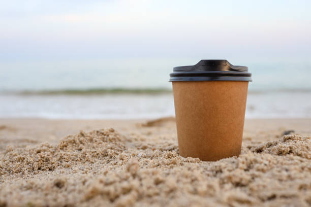 istock Paper coffee mugs Laying on the sandy beach in summer. 1402091355