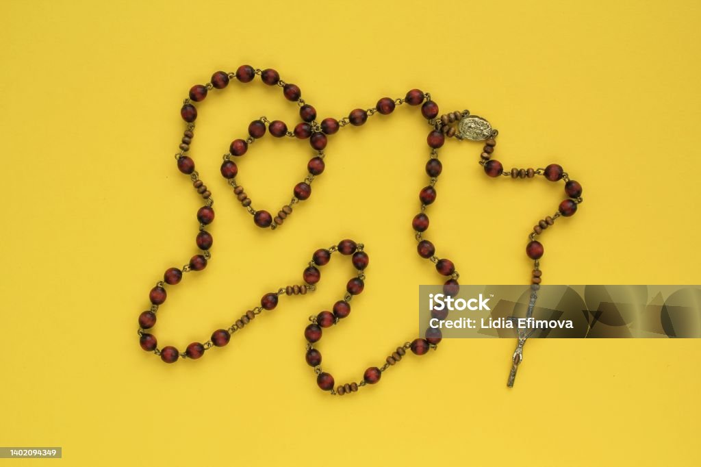 Rosary wooden beads and crucifix christian cross on yellow background. Rosary wooden beads and crucifix christian cross on yellow background. Catholic symbol. Flatlay, top view, lay out, isolated. Pray for God, faith in Jesus Christ and believe religion concept. Closeup Altar Stock Photo