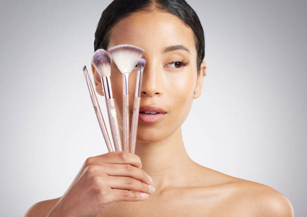 istock A beautiful mixed race woman posing with a collection of makeup brushes during pamper routine. Hispanic model with cosmetic tools standing against a grey copyspace background 1402094895