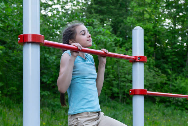 istock Sportive teenage girl is making pull ups on the horizontal bar 1402094957