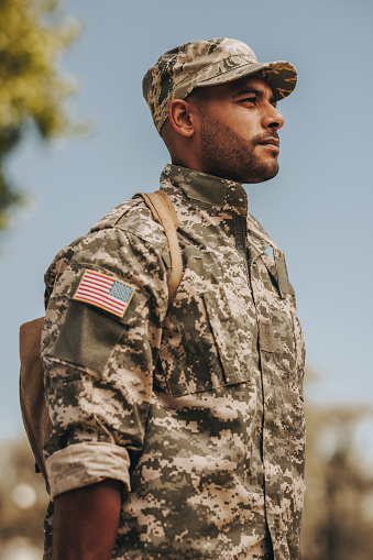 Patriotic young soldier standing at attention outside his home. Courageous American serviceman coming back home after serving his country in the military.