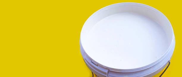 istock White paint in plastic bucket on yellow background. 1402097300