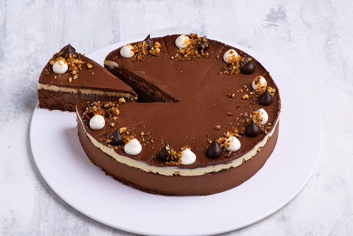 A closeup shot of a single-layered chocolate cake on a white plate