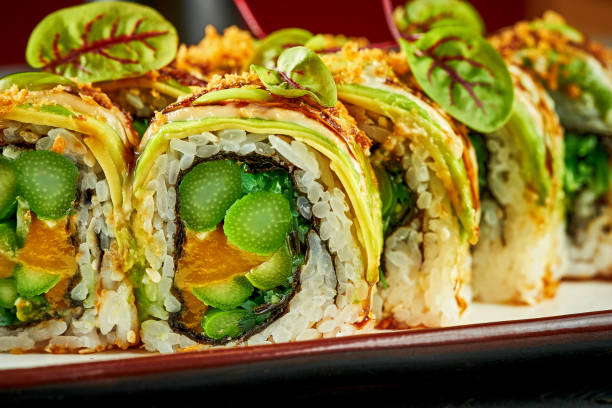 istock Vegetarian sushi rolls with avocado, mango and sauces isolated on a white plate. Close-up 1402097703