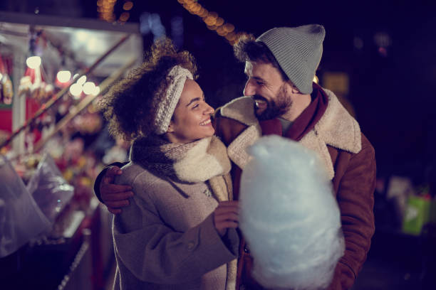 istock Happy couple talking while eating cotton candy on market by night. 1402098711