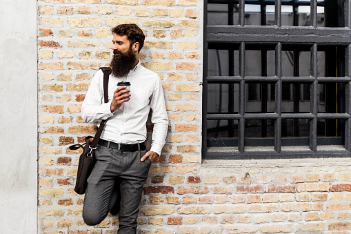 Bearded young man against brick wall
