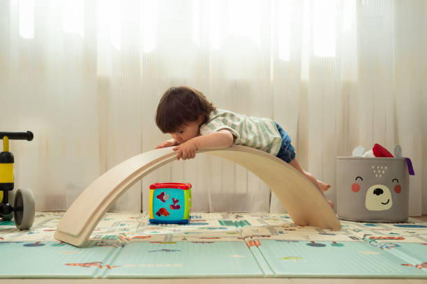 Girl playing with a balance board as if it were a slide. Little girl playing with a balance board as if it were a slide. babyhood stock pictures, royalty-free photos & images