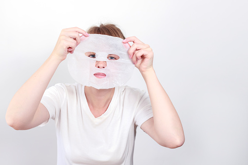 a woman with a fabric cosmetic mask on a white background