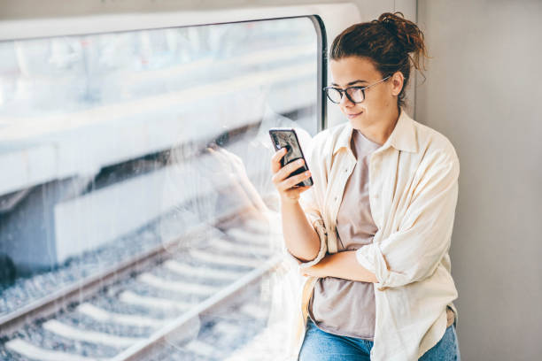 Young woman traveling by train and using phone. stock photo