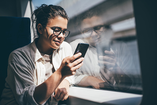 Young woman traveling by train and using phone.