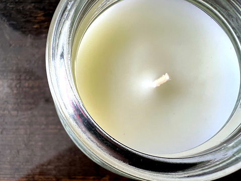 A macro image of a white candle in the glass from above.