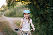 Smiling happy child girl on bike holding bottle of water