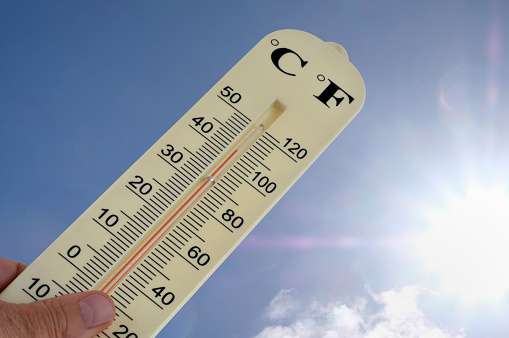 Thermometer with a double graduation degree centigrade and degree fahrenheit against a background of sunny sky