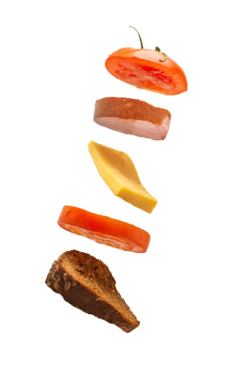 Flying deconstructed sandwich made of slices of bread, tomato, cheese and ham on a white background. Levitation of a simple sandwich. Isolated.