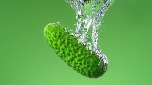 Cucumber Falling into Water and Making Air Bubbles in Slow Motion on the Green Background