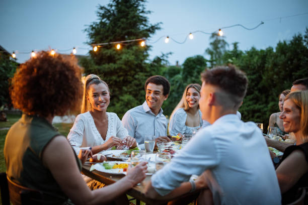 Friends and family eating dinner outdoors on warm summer night stock photo