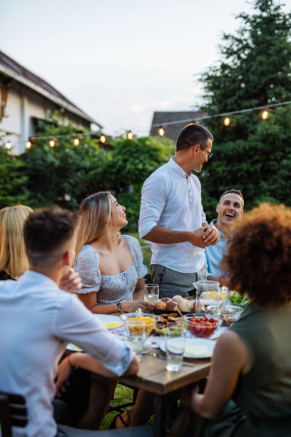 Man having speech during outdoor dinner with friends and family stock photo