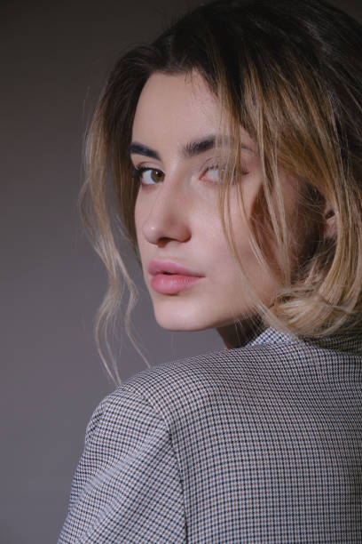 serious young woman in grey suit looking back over shoulder closeup view