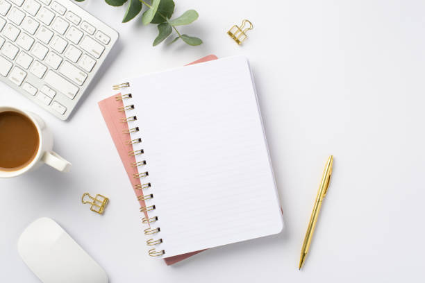 istock Business concept. Top view photo of workstation keyboard computer mouse eucalyptus cup of coffee gold pen binder clips and open notebook on isolated white background with empty space 1402105784