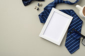 istock Father's Day concept. Top view photo of white photo frame blue necktie bow-tie glasses cup of coffee and cufflinks on isolated pastel grey background with blank space 1402106034
