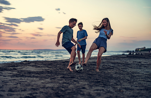 Kids playing football on beach. Summer day sunset. Three kids are fighting for the ball.
Canon R5