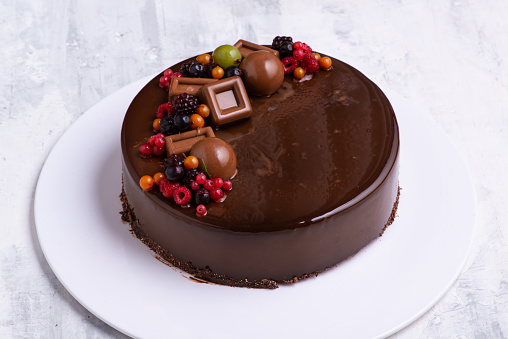An angle shot of a chocolate glaze cake decorated with berries.