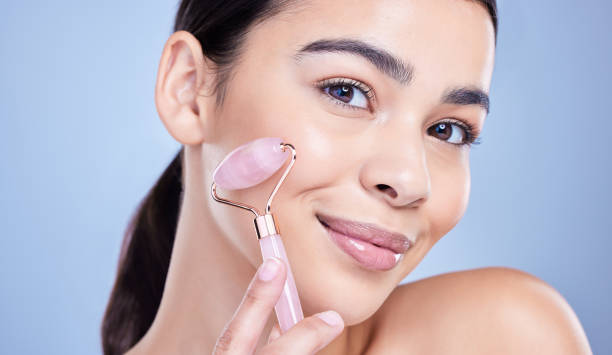 istock Studio Portrait of a beautiful mixed race woman using a rose quartz derma roller during a selfcare grooming routine. Young hispanic woman using anti ageing tool against blue copyspace background 1402107529