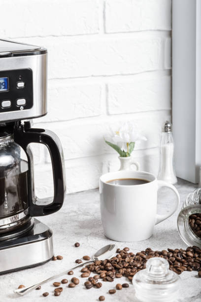 istock A white cup with a drink on the kitchen table next to a drip coffee maker. Roasted coffee beans. Morning in the kitchen 1402108492