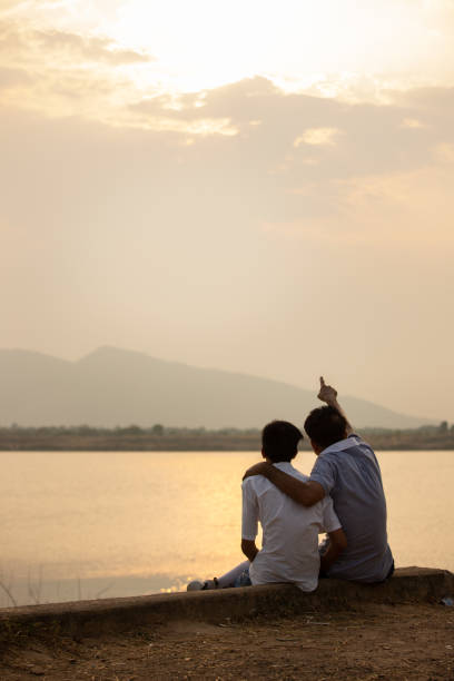 istock father and son sitting and watching the sunset 1402109536