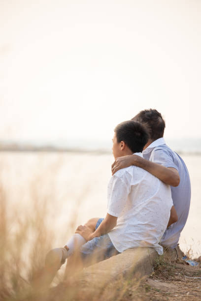 istock father and son sitting and watching the sunset 1402109573